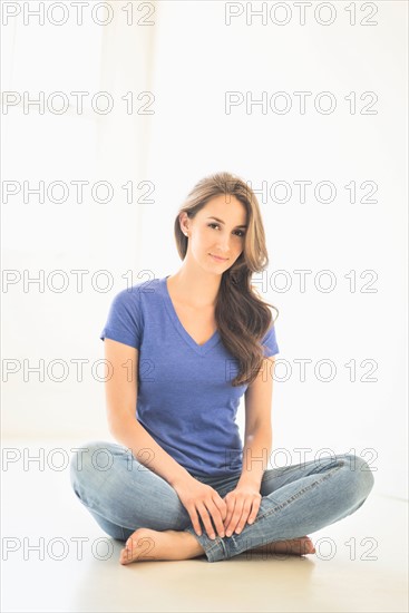 Portrait of young woman sitting on floor.
