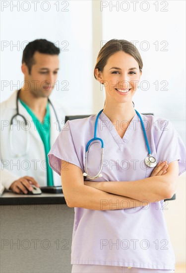 Female and male nurses at nurse's station in hospital.