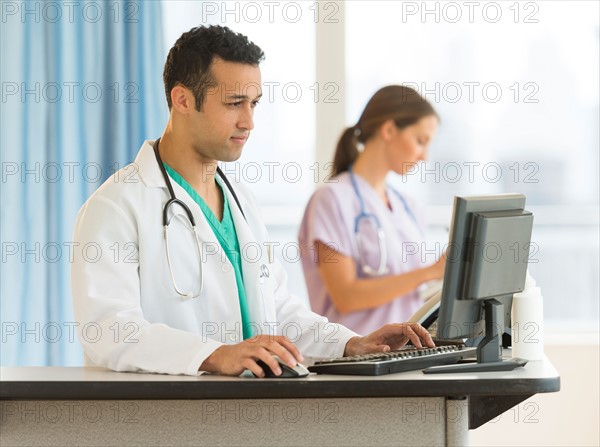 Male and female nurses working at nurse's station in hospital.