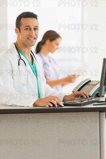 Male and female nurses working at nurse's station in hospital.