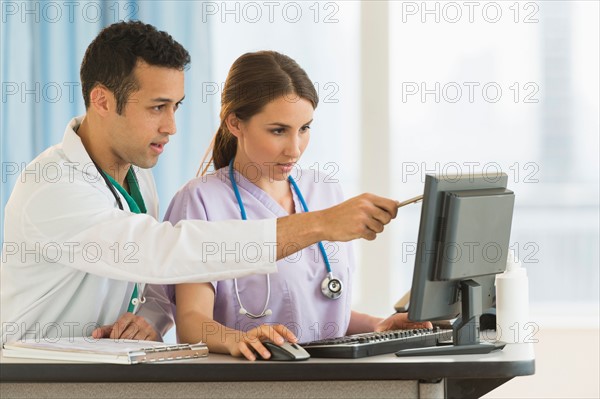 Male and female nurses working at nurse's station in hospital.