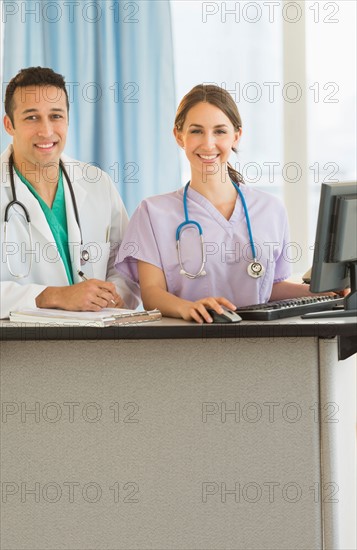 Portrait of male and female nurses at nurse's station in hospital.