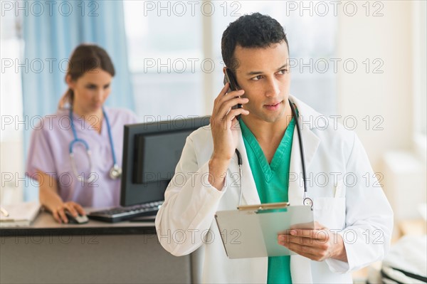 Male and female nurses working at nurse's station in hospital.