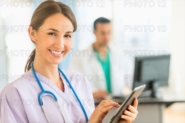 Female and male nurses working at nurse's station in hospital.