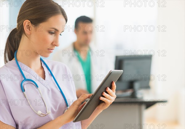 Female and male nurses working at nurse's station in hospital.