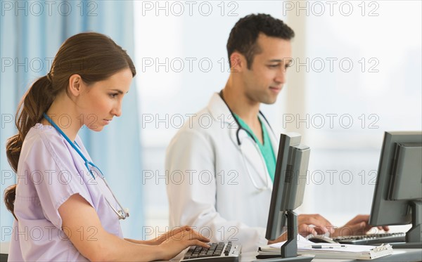 Male and female nurses working at nurse's station in hospital.