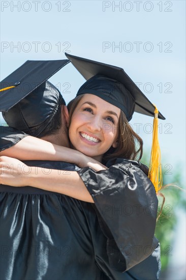 Female and male student embracing on graduation ceremony.