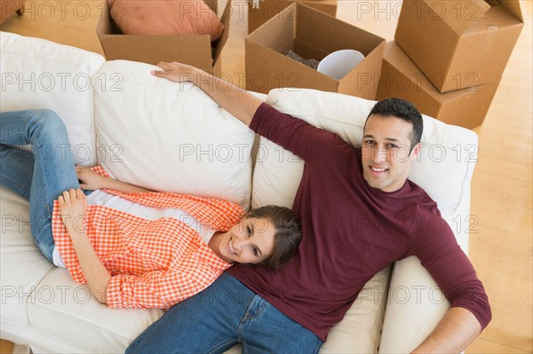 Young couple resting on sofa after moving into new home.