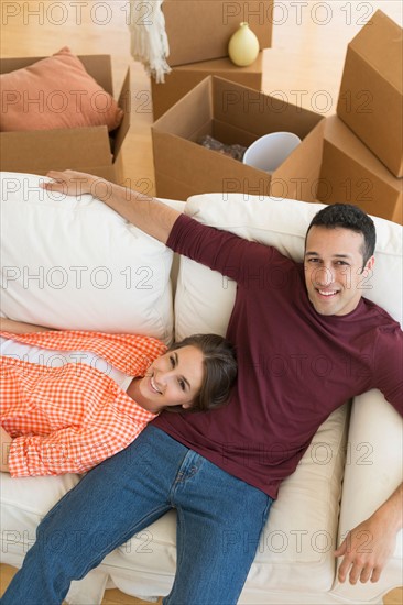 Young couple resting on sofa after moving into new home.