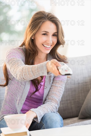 Young woman watching tv on sofa.