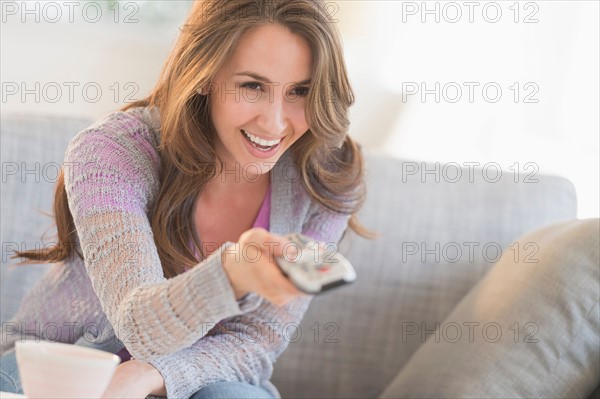 Young woman watching tv on sofa.