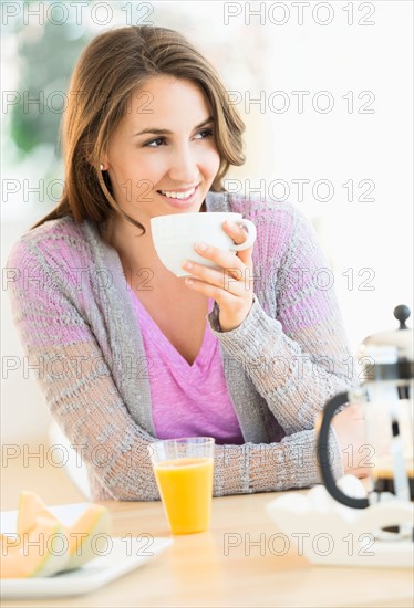 Young woman drinking tea at table.