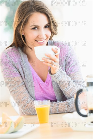 Portrait of young woman drinking tea at table.