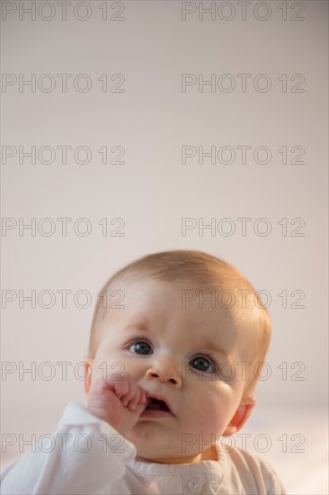 Portrait of baby girl (6-11 months) sitting in bed with stack of books