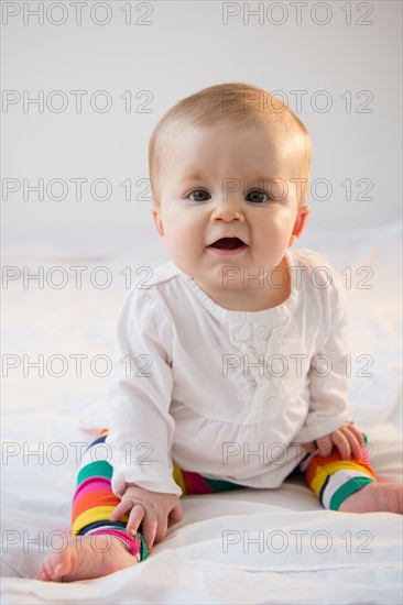 Portrait of baby girl (6-11 months) sitting in bed