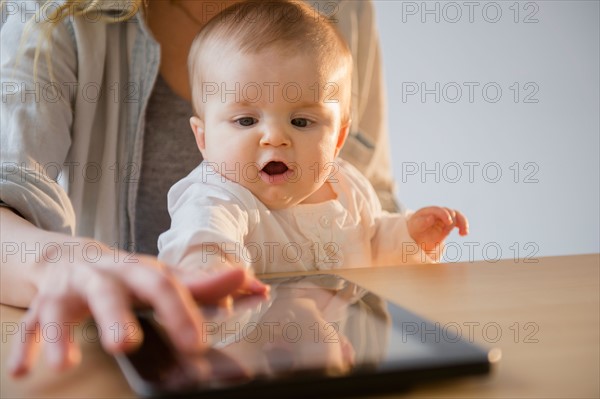 Mother and baby daughter (6-11 months) playing with digital tablet