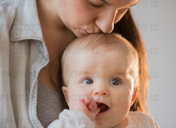 Mother kissing baby daughter (6-11 months)