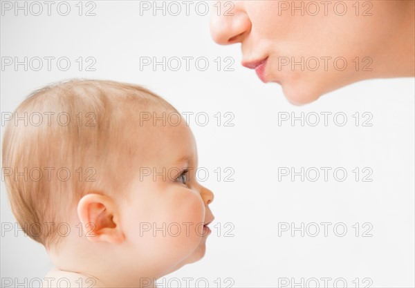 Side view of mother about to kiss her baby daughter (6-11 months)