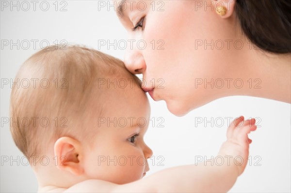 Side view of mother kissing her baby daughter (6-11 months)