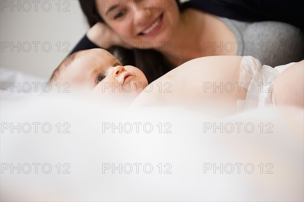 Portrait of mother and baby daughter (6-11 months) lying in bed