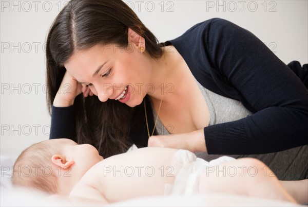 Portrait of mother and baby daughter (6-11 months) lying in bed