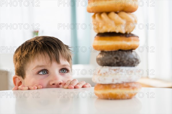 Portrait of boy (4-5) looking at stacked donuts