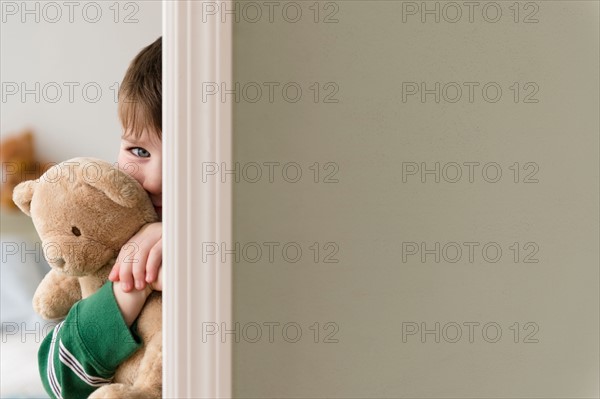 Portrait of boy (4-5) hiding behind wall