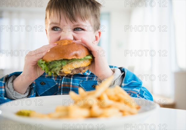 Portrait of boy (4-5) eating hamburger