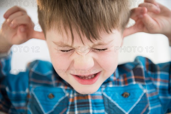 Portrait of boy (4-5) sticking fingers in his ears