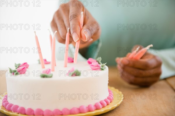Close up of woman's hands putting candles on birthday cake