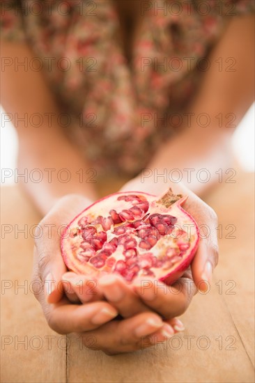 Close up of woman's hands holding pomegranate fruit