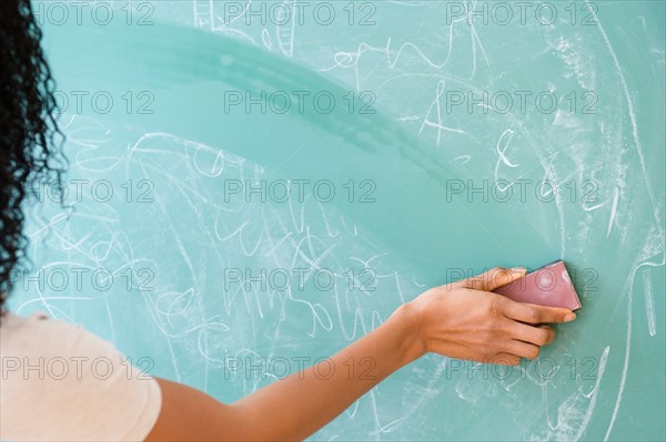 Rear view of woman erasing blackboard