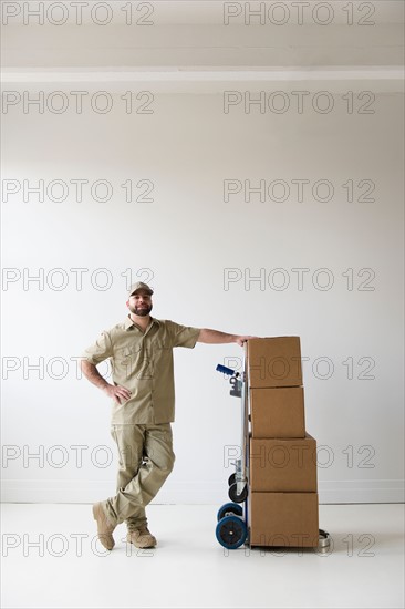 Portrait of delivery man standing next to push cart
