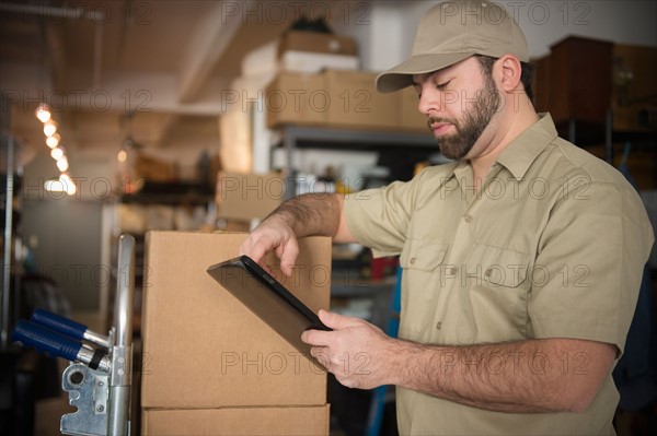 Delivery man in warehouse holding portable information device