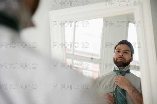 Reflection of man tying tie