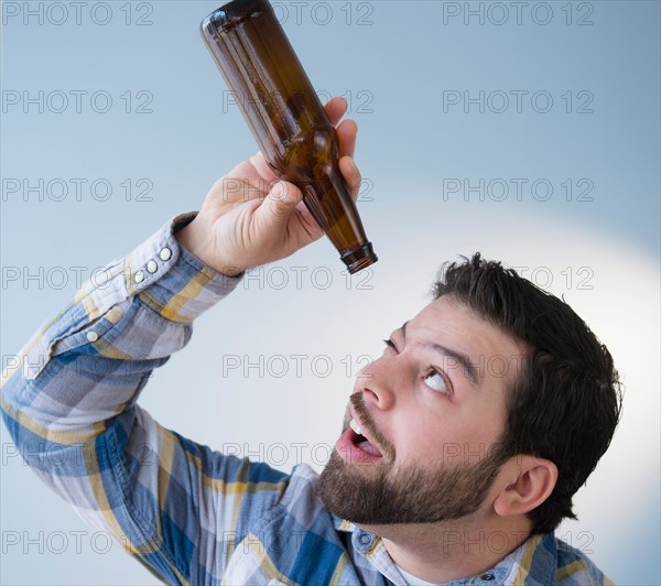 Portrait of man holding empty beer bottle and looking into it