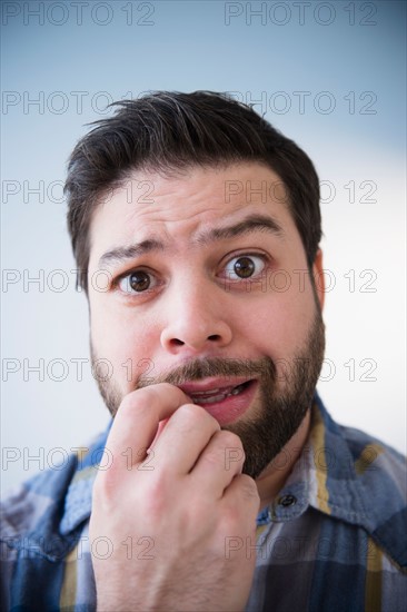 Portrait of nervous man biting nail