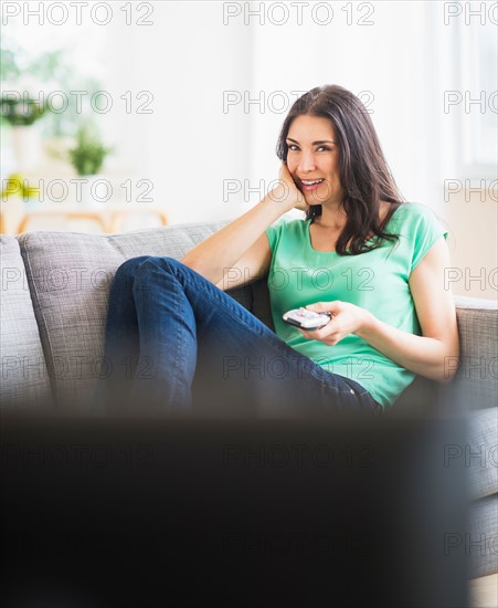 Portrait of woman watching TV on sofa