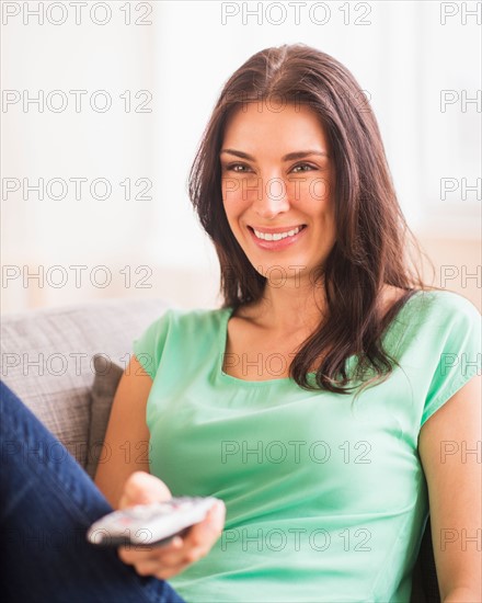 Portrait of woman watching TV on sofa