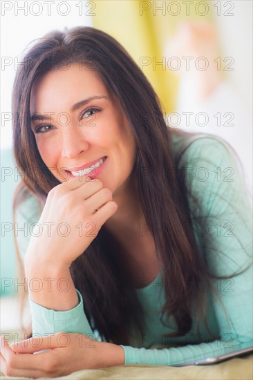 Portrait of woman lying down on bed with hand on chin, Close-up