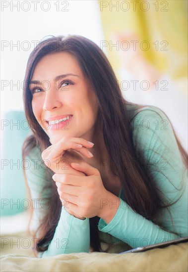 Portrait of woman lying down on bed with hand on chin, Looking up, Close-up