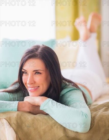 Portrait of woman lying down on bed with hand on chin, Looking away, Close-up