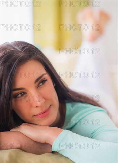 Portrait of woman lying down on bed with hand on chin, Looking away, Close-up