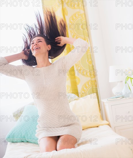 Portrait of woman kneeling on bed with hair tousled
