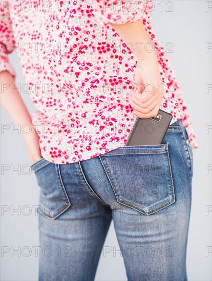 Rear view of woman with hand in pocket and mobile phone