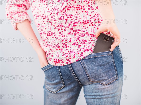 Rear view of woman with hand in pocket and mobile phone