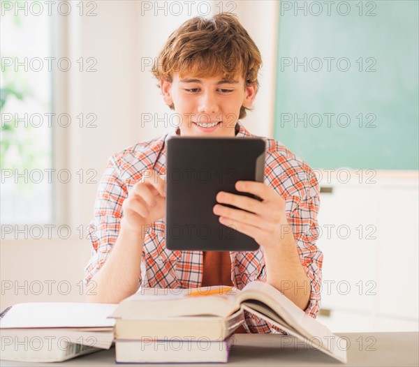 Teenage boy (14-15) sitting in classroom with tablet pc