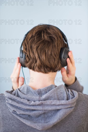 Rear view of teenage boy (14-15) wearing headphones