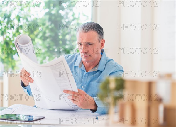 Portrait of man looking at blueprints in office