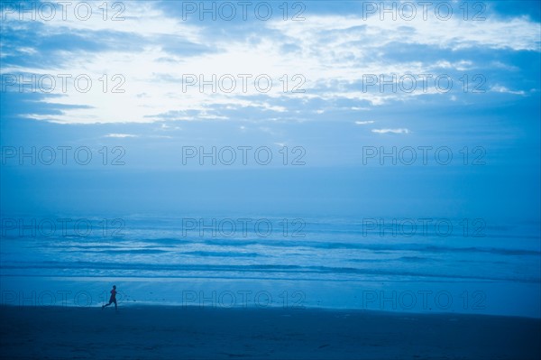 Distant view of woman running along beach